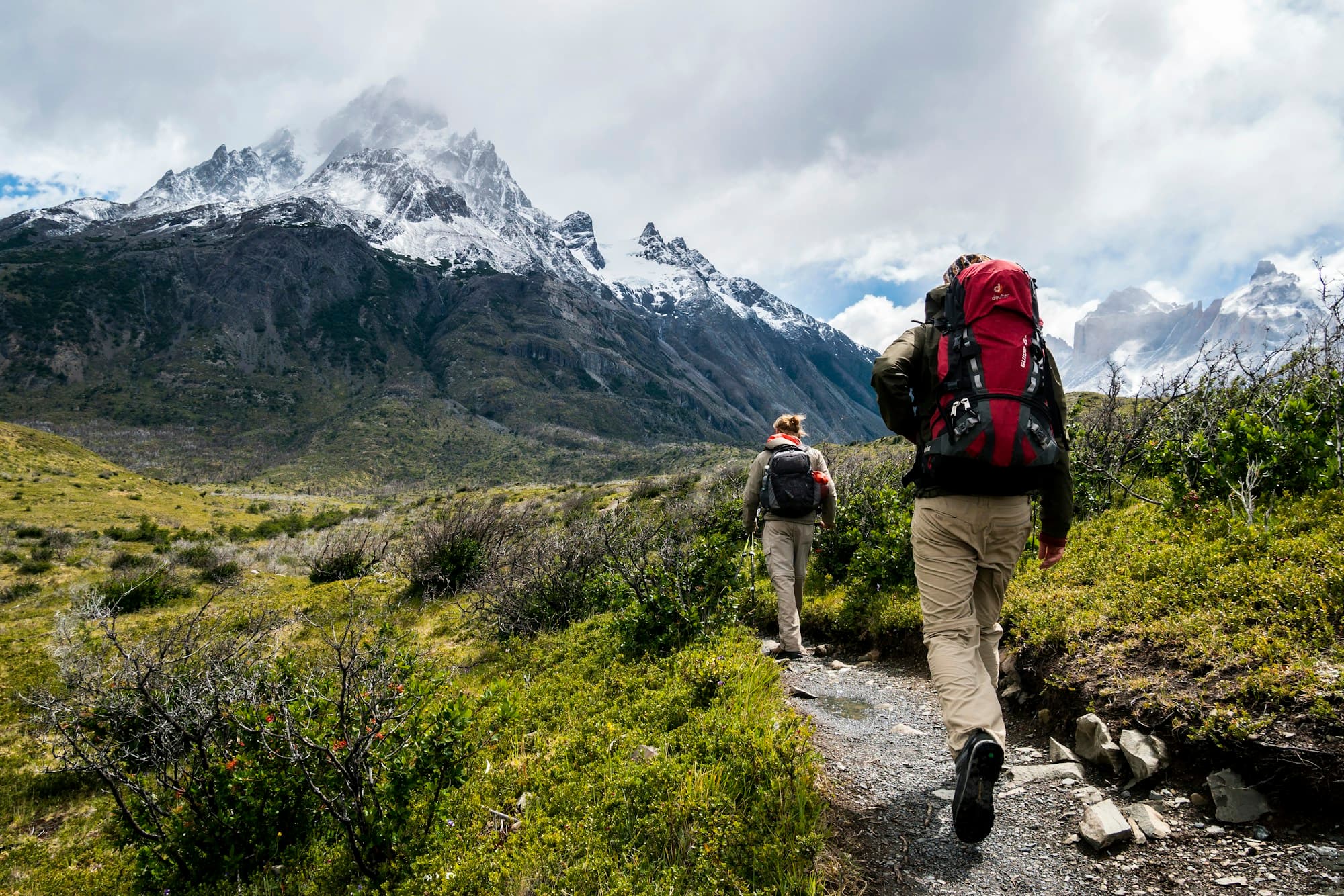 Backpacker on a high ridge trail in technical outdoor gear overlooking mountain terrain
